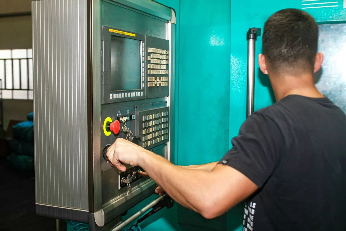 Machinist adjusting the controls on a CNC machine